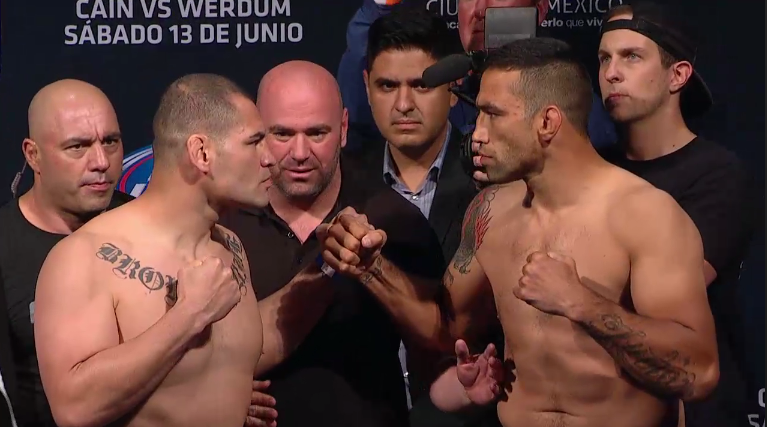 <a href='../fighter/Fabricio-Werdum'>Fabricio Werdum</a> and <a href='../fighter/Cain-Velasquez'>Cain Velasquez</a> face off at the UFC 188 weigh-in before their heavyweight title fight“ align=“center“ /></div><div readability=