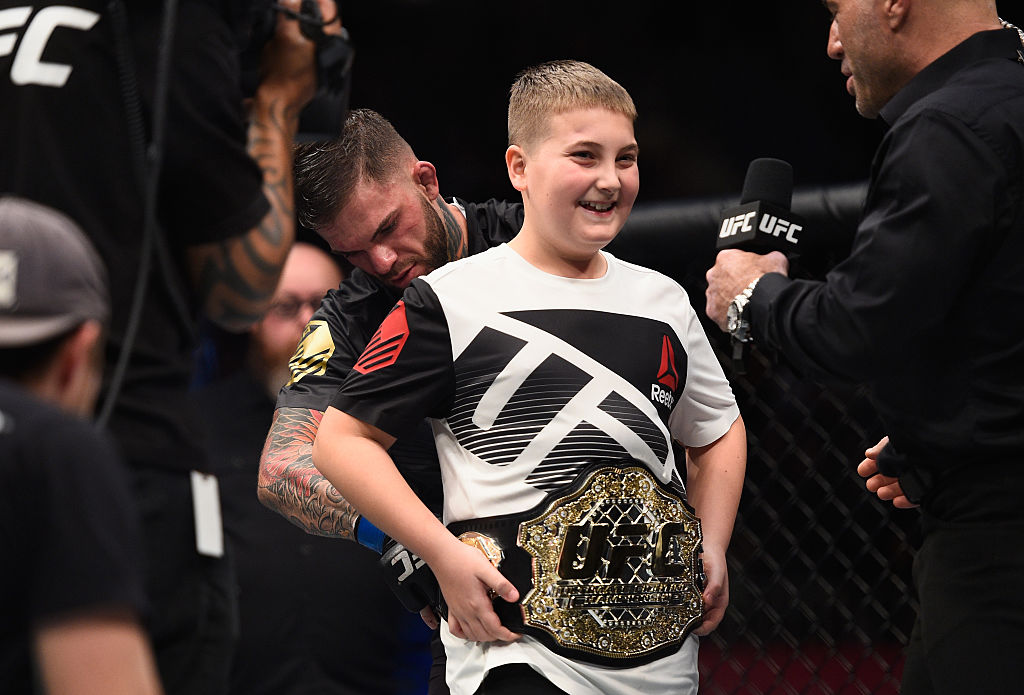 LAS VEGAS, NV - DEC. 30: Cody Garbrandt (back) places the UFC title belt around a young fan's wasit after defeating Dominick Cruz in their UFC bantamweight championship bout during the UFC 207 event at T-Mobile Arena. (Photo by Jeff Bottari/Zuffa LLC)