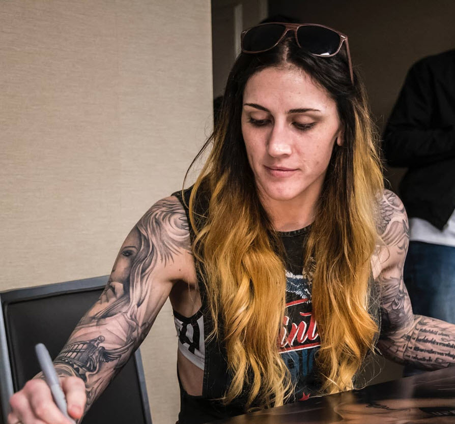 Megan Anderson signs posters at UFC 225 check-ins in Chicago.