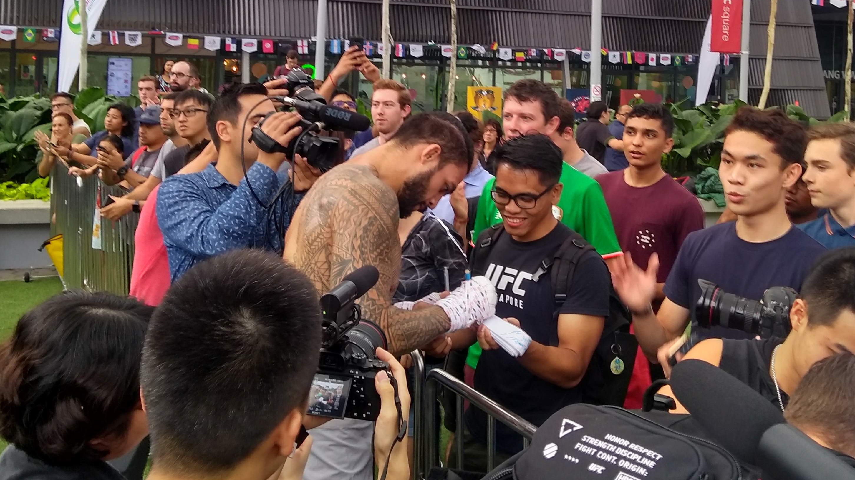 <a href='../fighter/tyson-pedro'>Tyson Pedro</a> signs autographs for fans following his open workout for Fight Night Singapore on 6/20/18 (Photo by Steve Latrell/Zuffa LLC)“ align=“left“/>Australian Tyson ‘Kangaroo Paws’ Pedro and his thousand-watt smile went next, and when host <a href=