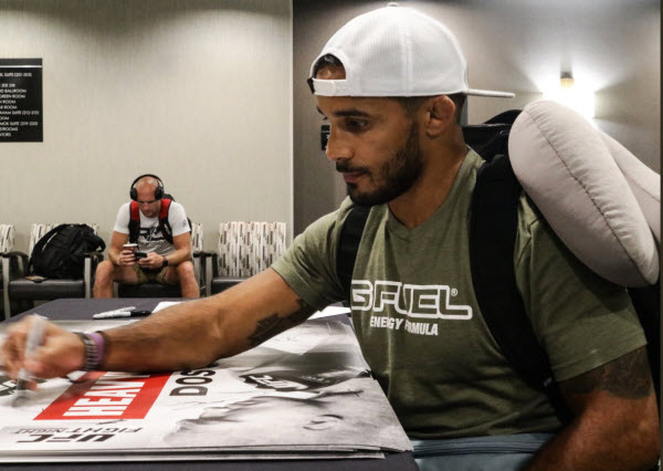 Dennis Bermudez signs posters at Fight Night Boise check-ins.